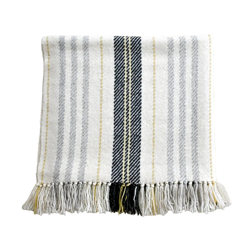 A striped blanket throw with a natural grey background and three thinner grey stripes, dark grey with smaller yellow stripes, and light yellow with smaller grey stripes, fringed at the ends.