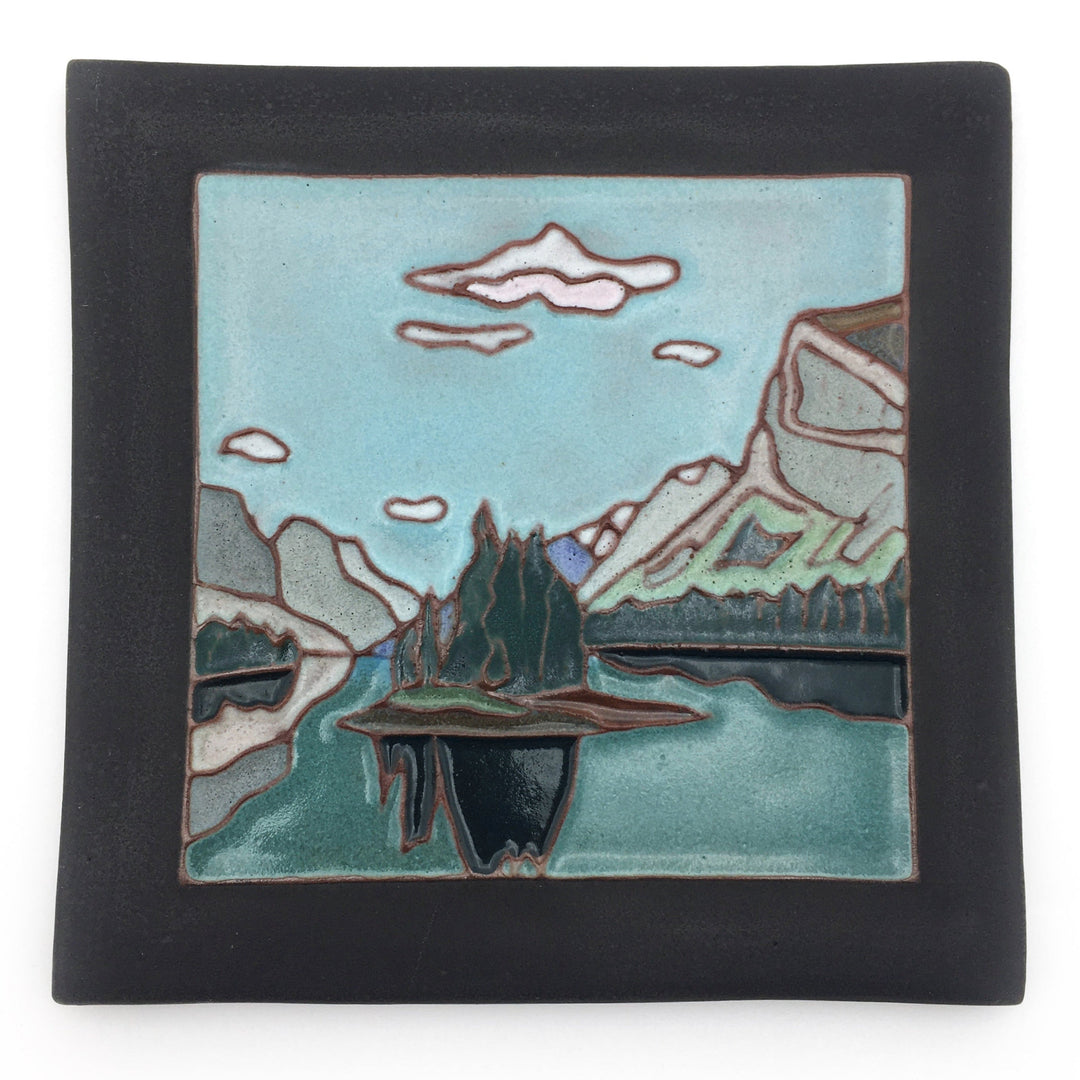 Decorative tile with a mountain and lake landscape design on a white background